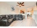 Open living room with hardwood floors, a ceiling fan, and a comfortable leather sectional couch at 3411 Holly Ave, Las Vegas, NV 89106