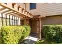 Charming front entryway with a wood pergola, brick accents, and lush greenery, creating a welcoming entrance at 3484 Nightflower Ln # B, Las Vegas, NV 89121