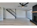 Spacious living room featuring a black fireplace, wood-look floors, black ceiling fan and staircase at 3484 Nightflower Ln # B, Las Vegas, NV 89121