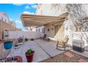 This backyard features a retractable awning, concrete patio, rock landscaping, white fencing and plenty of potted plants at 9339 Square Dance Pl # 103, Las Vegas, NV 89178