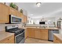 This kitchen features stainless steel appliances, wooden cabinets, granite countertops and views into the Gathering room at 9339 Square Dance Pl # 103, Las Vegas, NV 89178