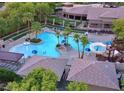 Aerial view of a community pool with a slide, surrounded by palm trees and a clubhouse at 10217 Queens Church Ave, Las Vegas, NV 89135