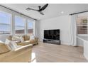 Open concept living room featuring modern ceiling fan, plank floors, neutral paint, and large windows with curtains at 5398 Pico Viejo St, Las Vegas, NV 89166