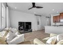 Open concept living room featuring modern ceiling fan, plank floors, neutral paint, large windows, and TV at 5398 Pico Viejo St, Las Vegas, NV 89166