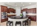 Gourmet kitchen showcasing dark wood cabinetry, stainless steel appliances, a central island, and counter seating at 75 Luce Del Sole # 3, Henderson, NV 89011