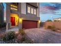 Close up of two-story home with a brick driveway, red garage door, and a red front door with silver accents at 8012 Carpenter Creek Ave, Las Vegas, NV 89113