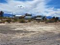 Exterior view of a residence, showing desert landscaping under a partly cloudy sky and distant mountain views at 81 W Mesquite Ave, Pahrump, NV 89060