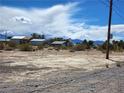 Exterior view of a residence, showing desert landscaping under a partly cloudy sky and distant mountain views at 81 W Mesquite Ave, Pahrump, NV 89060