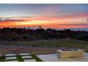 Spacious backyard with artificial grass, desert landscaping, and a fire pit under a colorful sunset sky at 1 Club Vista Dr, Henderson, NV 89052