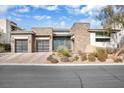 Contemporary home boasts stone accents, well-maintained landscaping, and a three-car garage at 32 Hunting Horn Dr, Las Vegas, NV 89135