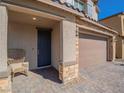 Welcoming front porch features brick accents, a cozy chair, and a dark blue front door leading to the home's entry at 4138 Bayley Skye Ave, Las Vegas, NV 89141