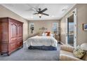 Cozy bedroom features an armoire, plush carpet, ceiling fan, and door to the outside at 500 Pear Lake St, Las Vegas, NV 89138