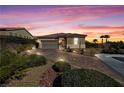 Charming single-story home showcasing a desert landscape, brick driveway, and a two-car garage beneath a picturesque sunset sky at 746 Royal Course Ct, Las Vegas, NV 89148