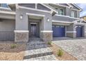 Home's covered front entrance showcasing stone pillars, stylish exterior lighting and a brick paved path at 7812 Alola Springs Ln # Lot 1, North Las Vegas, NV 89084