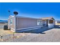 Exterior angle view of a single-story home with a covered porch and spacious gravel surroundings at 3581 W Dyer Rd, Pahrump, NV 89048