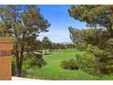 Picturesque view of a lush green golf course, framed by mature pine trees and a clear blue sky at 4961 Tierra Del Sol Dr, Las Vegas, NV 89113