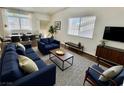 Bright living room featuring stylish blue sofas and a view into the dining area at 6104 Hillside Bloom Ct # 201, Las Vegas, NV 89130
