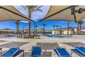 Resort-style pool area with lounge chairs and palm trees offers a relaxing oasis for residents to enjoy at 6952 Midnight Bronze St, North Las Vegas, NV 89086