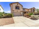 View of the front exterior of this tan home with a concrete driveway and desert landscaping at 774 Wigan Pier Dr, Henderson, NV 89002