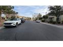 Neighborhood street with parked cars, homes and trees under a partly cloudy sky at 8824 Martin Downs Pl, Las Vegas, NV 89131