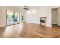 Open-concept living room featuring wood floors, a ceiling fan, fireplace and sliding doors leading to the patio at 668 Look Lively Ct, Henderson, NV 89011