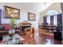 Elegant dining room with hardwood floors, complemented by a chandelier, large arched window, and curated artwork at 8262 Huxley St, Las Vegas, NV 89123