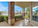 Charming front porch with stone pillars, offering a cozy seating area and views of the landscaped yard at 8800 Las Olivas Ave, Las Vegas, NV 89147