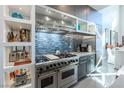 Gourmet kitchen featuring stainless steel appliances, custom cabinets, and a blue tile backsplash at 10605 Harvest Green Way, Las Vegas, NV 89135