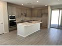 Modern kitchen boasts an island, gray cabinets, stainless steel appliances, and wood-look tile flooring at 145 Medianoche St, Las Vegas, NV 89138