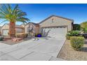 A single-story home showcasing desert landscaping, a palm tree and two-car garage under a blue sky at 2520 Eclipsing Stars Dr, Henderson, NV 89044