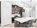 Modern kitchen with stainless steel appliances, dark wood cabinets, and a white quartz countertop island at 2536 Catallo St, Henderson, NV 89044