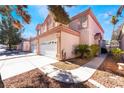 Two-story home boasting a three-car garage, complemented by desert landscaping and a meticulously maintained driveway at 4451 Tomer Ln, Las Vegas, NV 89121