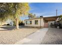 View of the home's side yard featuring gravel landscaping, a covered patio, and mature trees at 478 S Water St, Henderson, NV 89015