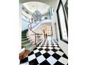 An elegant foyer showcases black and white tile floors and a grand curved staircase with chandelier at 7220 Shenandoah Springs Ave, Las Vegas, NV 89131