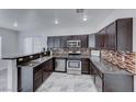 Modern kitchen with stainless steel appliances, dark cabinetry, granite countertops, and a mosaic backsplash at 840 Sheerwater Ave, Henderson, NV 89052