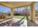 Covered patio offering shade with a view of the manicured backyard with artificial turf and palm trees at 9379 Arrowhead Bluff Ave, Las Vegas, NV 89149