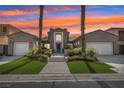 Beautiful two-story home featuring dual garages, a landscaped yard, and towering palm trees at sunset at 2690 Grassy Spring Pl, Las Vegas, NV 89135