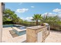 Outdoor kitchen with a built-in grill, sink, and mini-fridge, near the pool and spa area at 2690 Grassy Spring Pl, Las Vegas, NV 89135