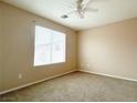 Bright, carpeted bedroom with neutral walls, a ceiling fan, and a large window providing ample natural light at 5236 El Prado Heights St, North Las Vegas, NV 89081