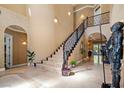 Spacious foyer with high ceilings, grand staircase, tile floors, and decorative knight armor at 9616 Grand Isle Ln, Las Vegas, NV 89144