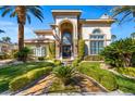 Elegant home with a grand entrance, lush landscaping, mature palms, and a beautiful walkway at 9616 Grand Isle Ln, Las Vegas, NV 89144