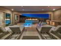 Stunning outdoor patio featuring a pool, fire feature, lounge chairs, and a built-in barbecue area at 10096 Amethyst Hills St, Las Vegas, NV 89148