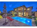 Backyard featuring a pool, manicured landscaping, patio area, and a view of the home's exterior at 12356 Grey Dunes Ave, Las Vegas, NV 89138