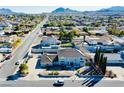 An aerial view of a neighborhood featuring a home with an extended driveway, a neutral-toned exterior and mountain views at 241 E Country Club Dr, Henderson, NV 89015