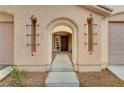 Inviting front entryway featuring an arched entrance, decorative sconces, and a well-maintained walkway at 5453 Brass Hills Ct, Las Vegas, NV 89122