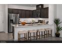 A kitchen features dark cabinets, stainless steel appliances, and a breakfast bar with stool seating at 6668 Nimbus Ave # Lot 22, Las Vegas, NV 89130