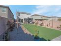 This backyard features artificial turf, a covered patio, and desert landscaping, offering a serene space for outdoor enjoyment at 4567 Chirping Cricket Ave, Las Vegas, NV 89141