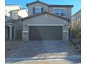 Two-story home with neutral siding and a large two-car garage with stone veneer accents and paved driveway at 8125 Glade Crossing Ave, Las Vegas, NV 89113
