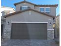 Two-story home with neutral siding and a large two-car garage with stone veneer accents at 8125 Glade Crossing Ave, Las Vegas, NV 89113