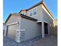 Two-story home with neutral siding, tile roof, and a two-car garage with stone veneer accents at 8125 Glade Crossing Ave, Las Vegas, NV 89113